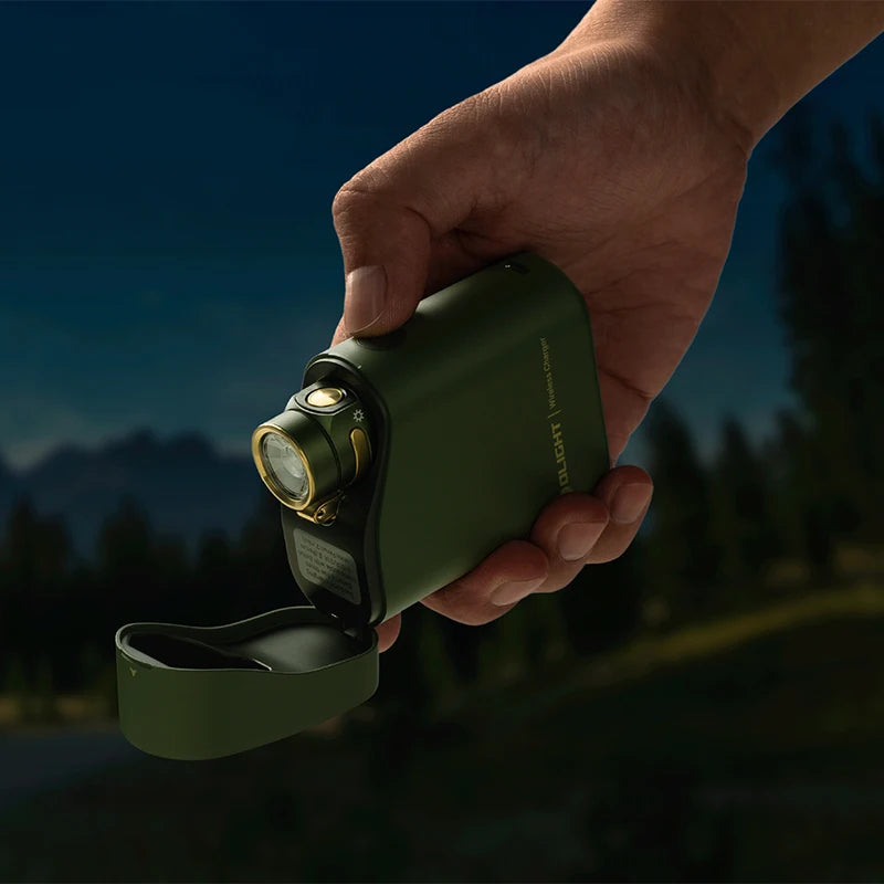 Hand holding a green flashlight with a mountainous background