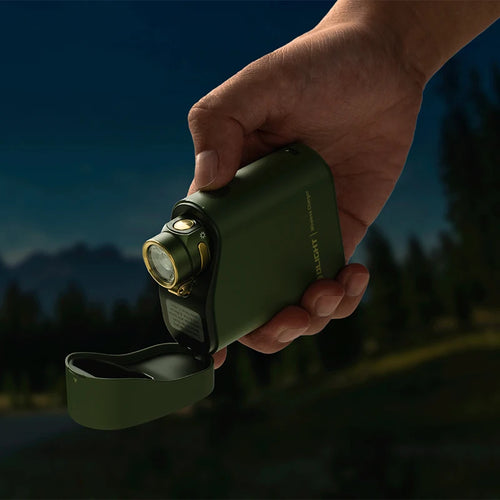 Hand holding a green flashlight with a mountainous background