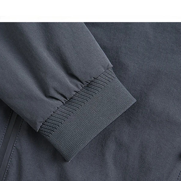 Close-up of a dark gray jacket with an adhesive zipper design, text overlay on a white background.
