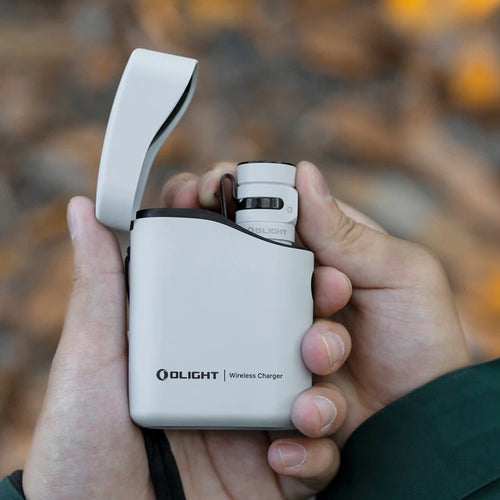 Hand holding a white Olight wireless charger against a blurred natural background