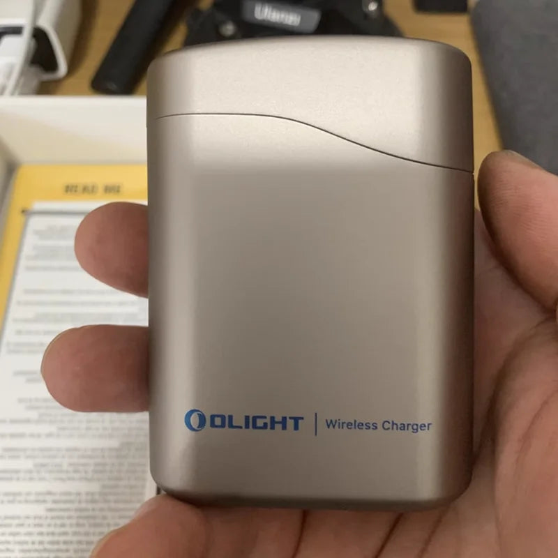 Olight wireless charger held in a hand with a blurred background